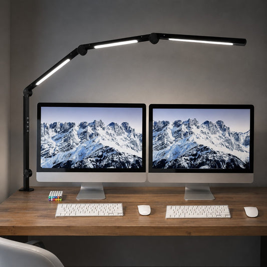 Black Melora LED desk lamp with swing arm, clamped to a desk with dual monitors